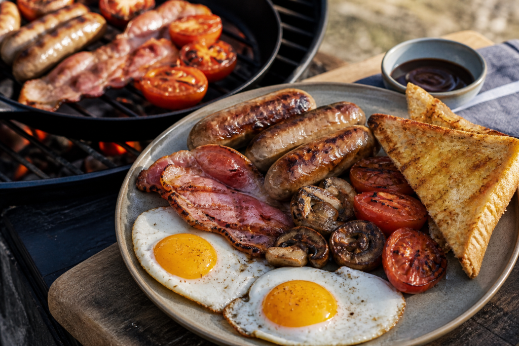 British breakfast BBQ with sausages bacon eggs mushrooms and tomatoes